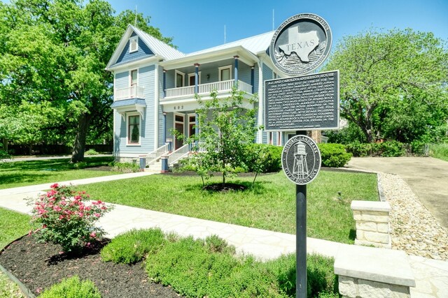 exterior space with a front lawn, covered porch, and a balcony