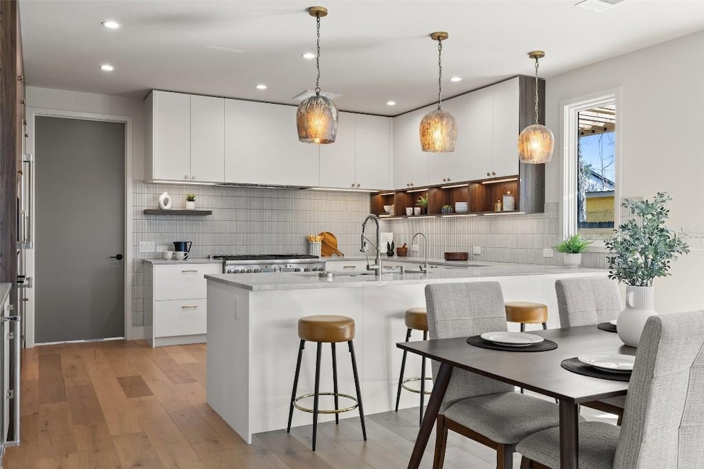 kitchen with white cabinetry, range, light wood-type flooring, and pendant lighting