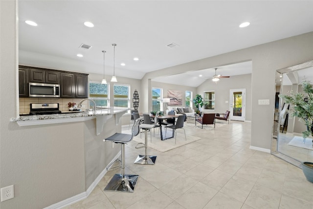 kitchen featuring light stone countertops, range, a wealth of natural light, and a kitchen breakfast bar