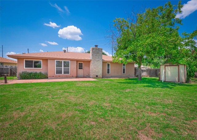 back of property featuring a lawn, a patio area, and a storage shed