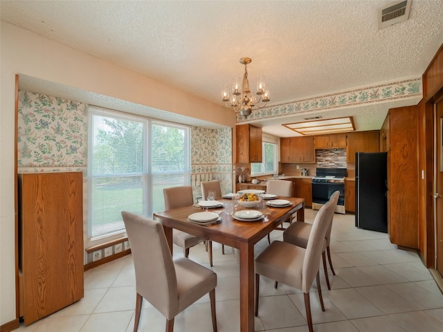 dining space with a notable chandelier, light tile patterned floors, a wealth of natural light, and a textured ceiling