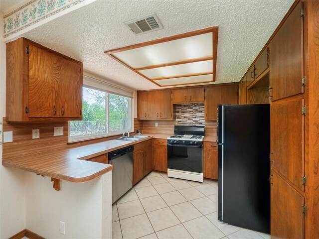 kitchen with stainless steel dishwasher, black fridge, sink, kitchen peninsula, and white range with gas stovetop