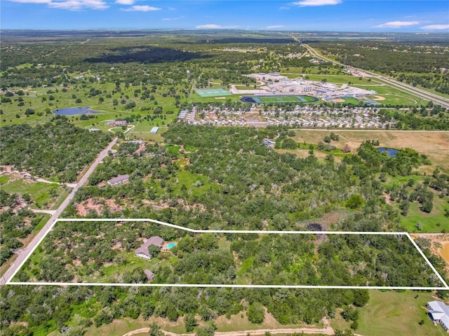 653 Leisure Ln, Cedar Creek, TX 78612 - aerial overview of property's location with a nearby body of water, property boundaries highlighted, and a heavily wooded area