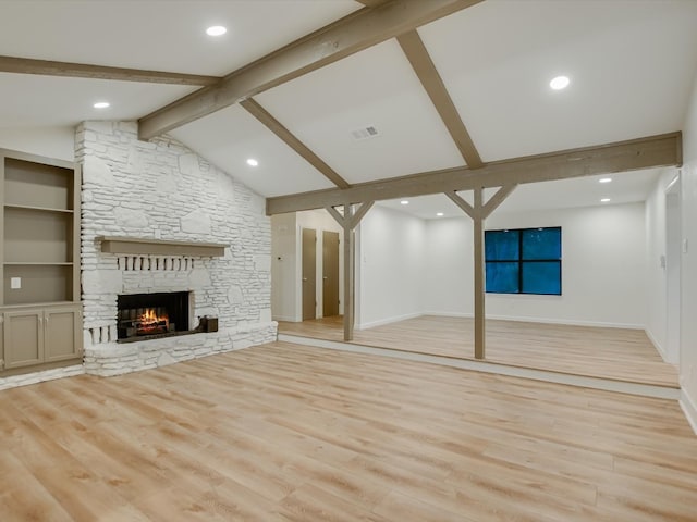 unfurnished living room featuring light wood-type flooring, lofted ceiling with beams, a stone fireplace, and built in features