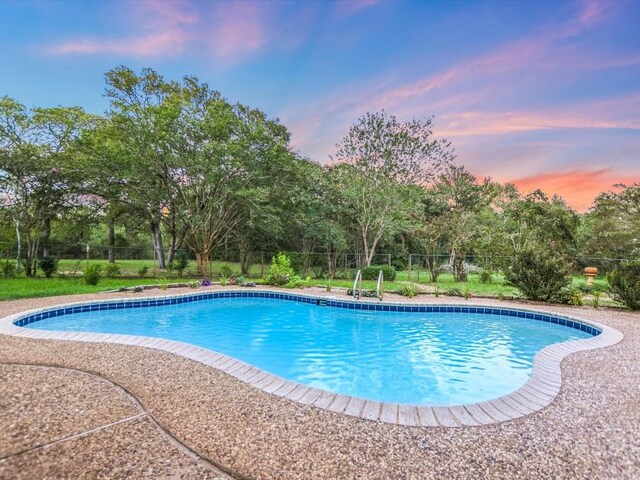 653 Leisure Ln, Cedar Creek, TX 78612 - pool at dusk with a fenced backyard and view of scattered trees