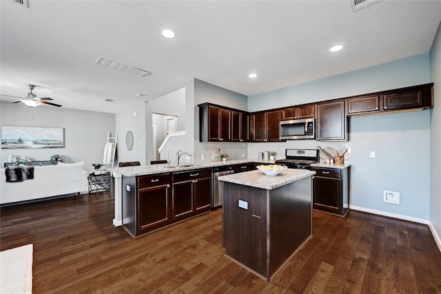 kitchen featuring light stone countertops, sink, a center island, and stainless steel appliances