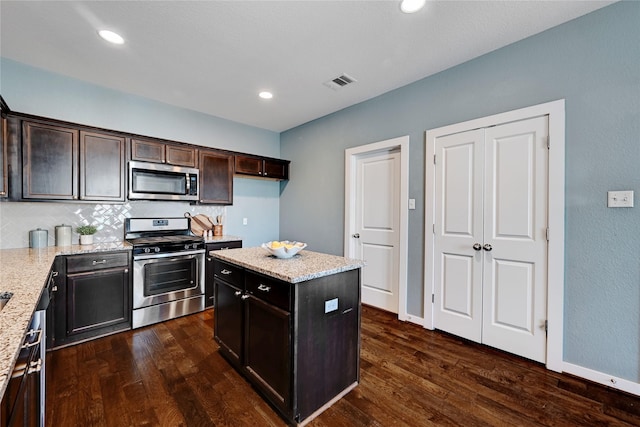 kitchen featuring light stone countertops, a center island, dark hardwood / wood-style floors, and appliances with stainless steel finishes