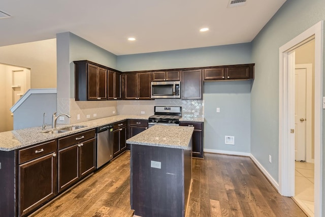 kitchen featuring sink, stainless steel appliances, light stone counters, and hardwood / wood-style floors