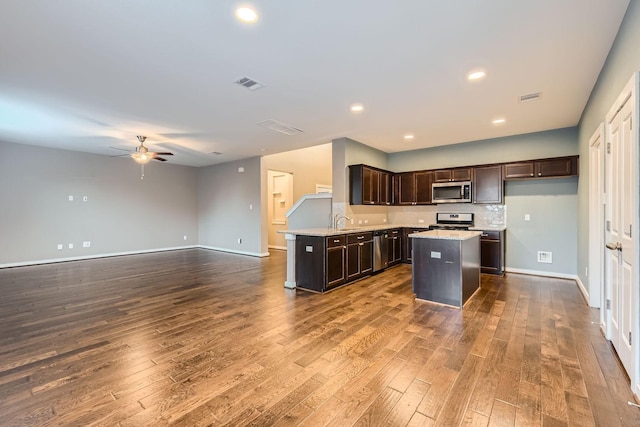 kitchen with hardwood / wood-style floors, appliances with stainless steel finishes, sink, a kitchen island, and dark brown cabinets