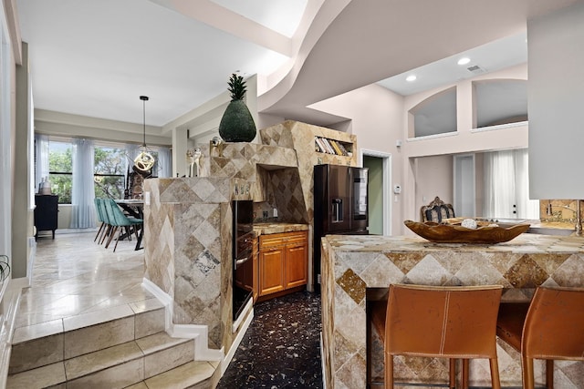 kitchen with light stone counters, a breakfast bar, a high ceiling, and black appliances