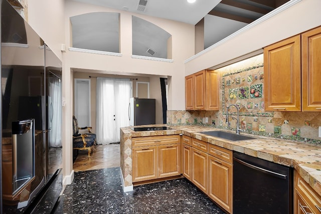 kitchen featuring a towering ceiling, sink, decorative backsplash, and black appliances