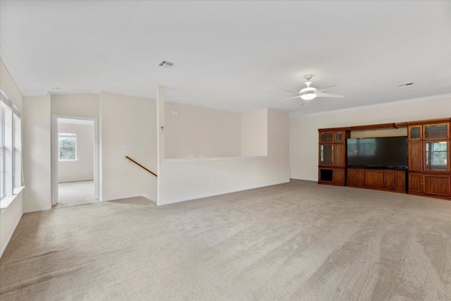 unfurnished living room with ceiling fan, lofted ceiling, ornamental molding, and light colored carpet