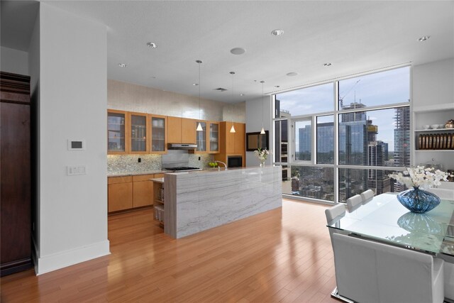 kitchen featuring light brown cabinets, decorative backsplash, a kitchen island, light hardwood / wood-style flooring, and sink