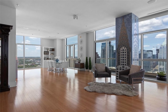 living room with a wall of windows, plenty of natural light, a view of skyline, and wood finished floors