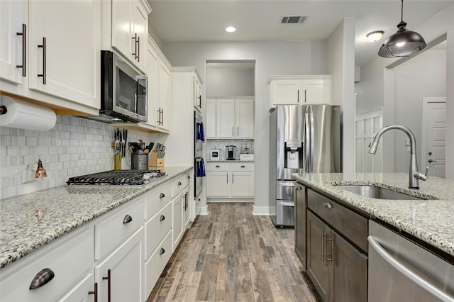 kitchen with hanging light fixtures, white cabinetry, sink, and stainless steel appliances