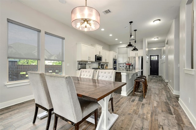 dining space with wood-type flooring and a notable chandelier