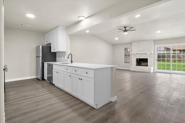 kitchen with a stone fireplace, sink, wood-type flooring, and white cabinetry