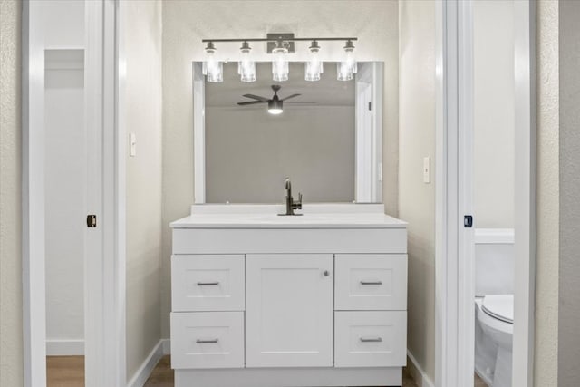 bathroom with hardwood / wood-style floors, vanity, ceiling fan, and toilet