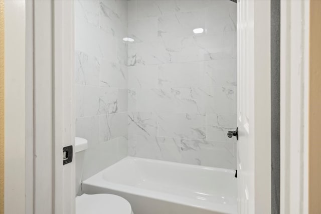 bathroom featuring tiled shower / bath combo and toilet