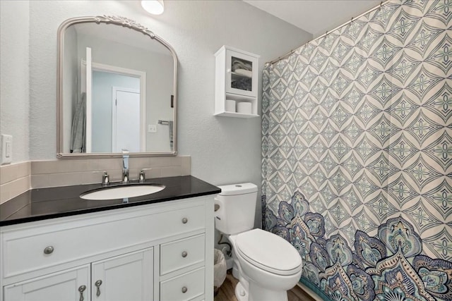 bathroom with vanity, toilet, and backsplash