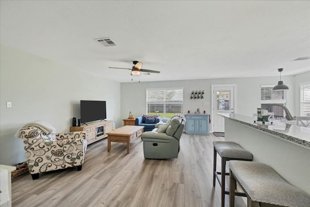 living room with ceiling fan, plenty of natural light, and light wood-type flooring