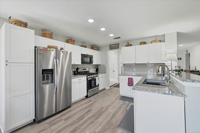 kitchen with white cabinetry, sink, light stone counters, and appliances with stainless steel finishes