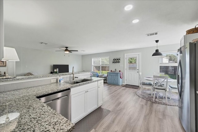 kitchen with sink, light stone counters, pendant lighting, white cabinets, and appliances with stainless steel finishes