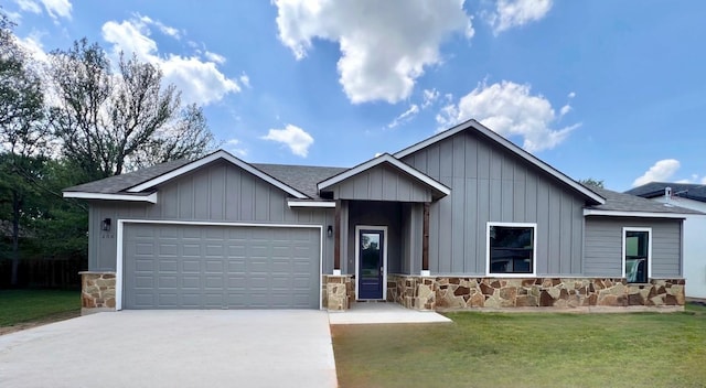 view of front of property featuring a front yard, stone siding, an attached garage, and concrete driveway