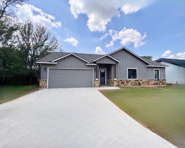 ranch-style house featuring an attached garage, a shingled roof, stone siding, driveway, and a front yard