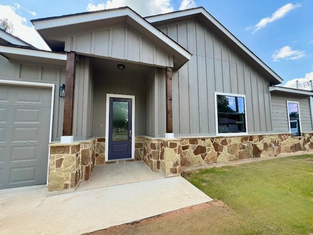 doorway to property featuring board and batten siding, stone siding, and an attached garage