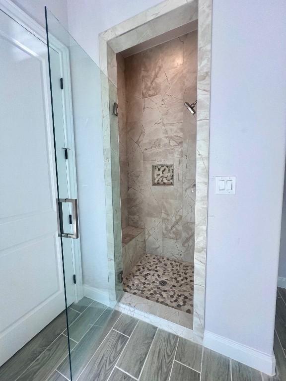 full bathroom with wood tiled floor, a shower stall, and baseboards