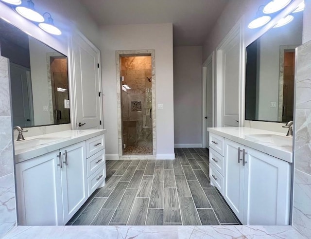 full bath with a shower stall, two vanities, a sink, and wood finish floors