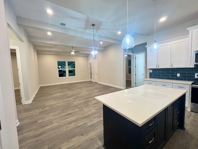 kitchen with stainless steel appliances, white cabinetry, dark cabinetry, backsplash, and a center island