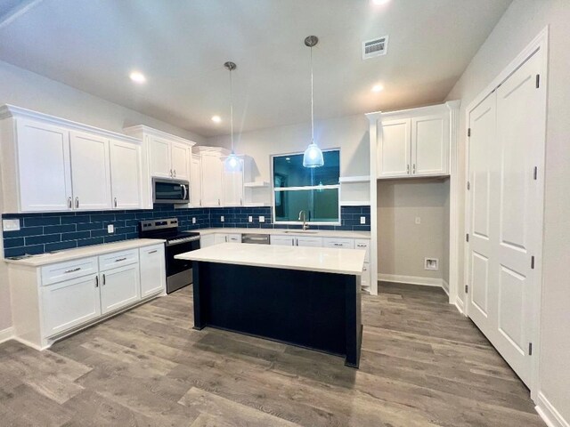 kitchen with light wood finished floors, decorative backsplash, appliances with stainless steel finishes, white cabinetry, and open shelves