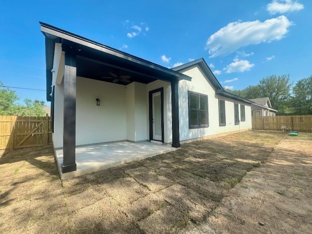 rear view of property with ceiling fan, a patio, fence, and stucco siding