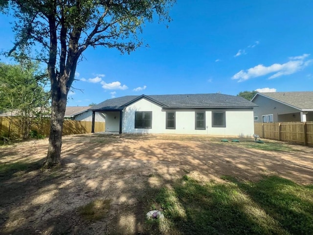 rear view of house with fence and stucco siding