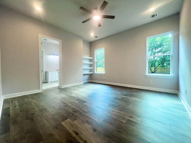 empty room featuring dark wood-style floors, visible vents, ceiling fan, and baseboards