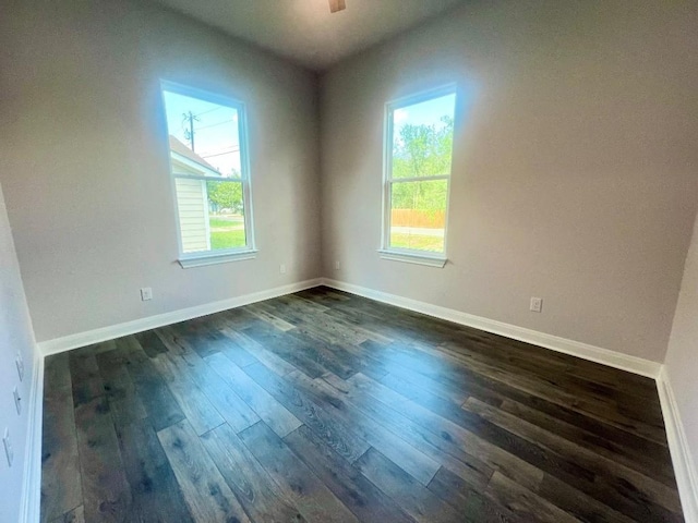 spare room featuring dark wood finished floors and baseboards