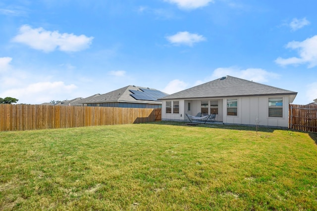 back of property featuring a lawn and solar panels