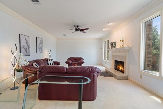 carpeted living room featuring a wealth of natural light, a premium fireplace, ceiling fan, and crown molding