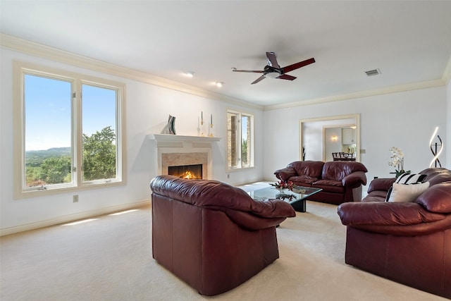 carpeted living room featuring plenty of natural light, a fireplace, crown molding, and ceiling fan