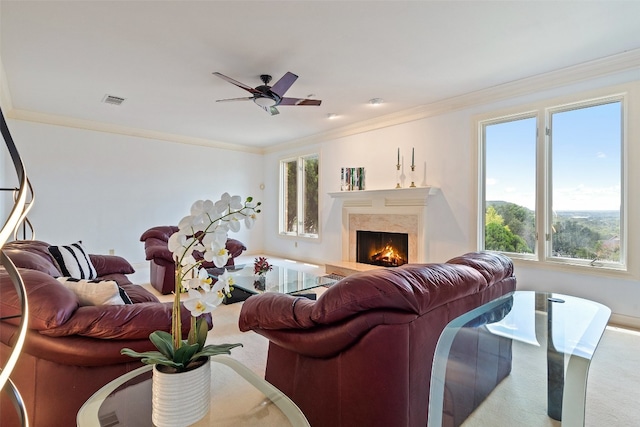 living room featuring plenty of natural light, a premium fireplace, ceiling fan, and ornamental molding