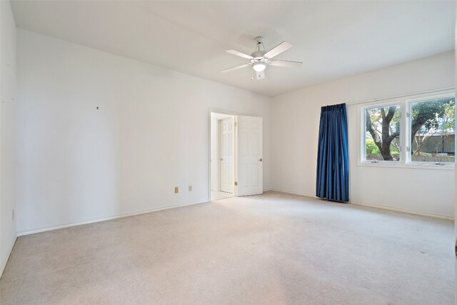 empty room featuring ceiling fan and light carpet