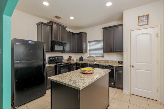 kitchen with dark brown cabinets, black appliances, light stone countertops, light tile patterned floors, and a center island