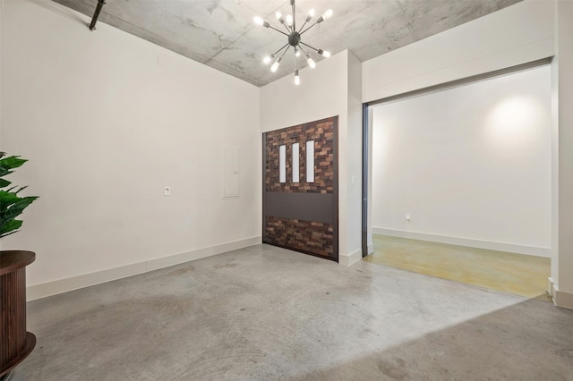 spare room featuring an inviting chandelier and concrete flooring