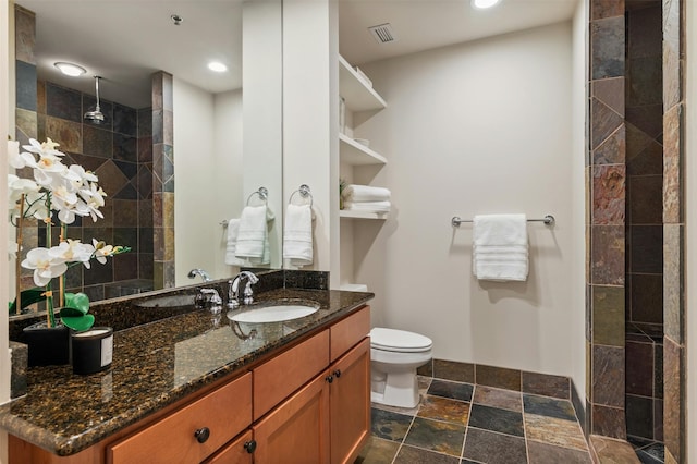 bathroom featuring tiled shower, vanity, and toilet