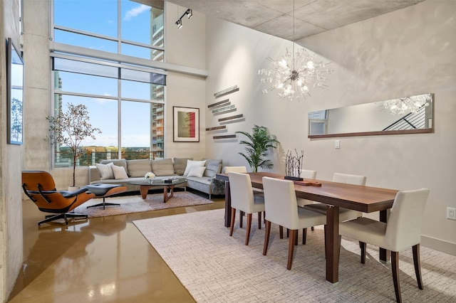 dining room with a notable chandelier, a wealth of natural light, concrete floors, and a high ceiling