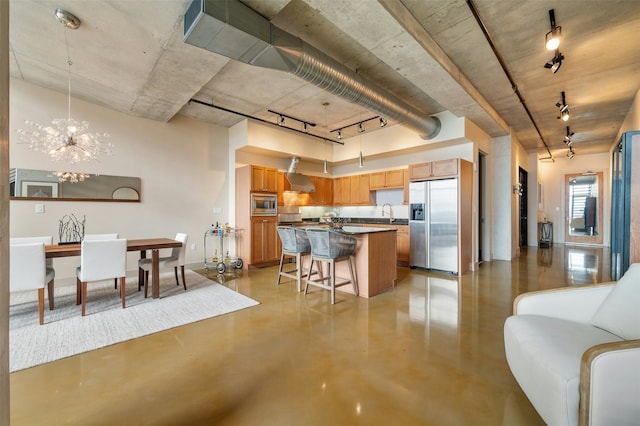 kitchen with appliances with stainless steel finishes, a kitchen bar, hanging light fixtures, a center island, and a notable chandelier