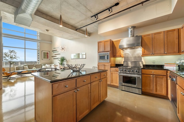 kitchen featuring rail lighting, stainless steel appliances, a center island, tasteful backsplash, and wall chimney exhaust hood