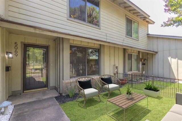 view of exterior entry featuring board and batten siding and fence